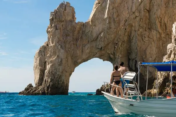 Couple sur un bateau devant l'arche de la plage de l'amour dans l'Etat de Baja California