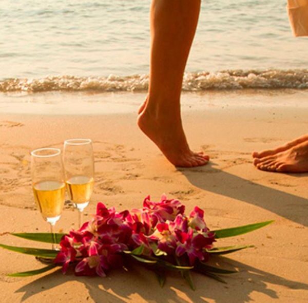 Couple s'embrassant sur une plage avec des coupes de champagnes