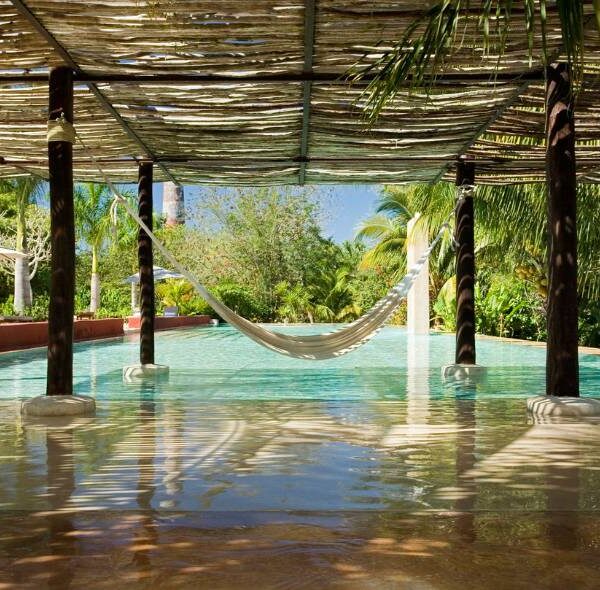 Magnifique piscine d'un hôtel avec un hamac suspendue au dessus de l'eau